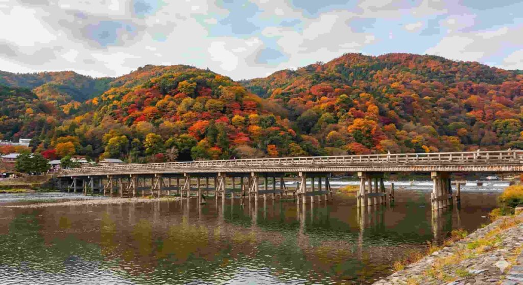 Togetsukyo Bridge in Arashiyama crossing the Katsura River with autumn leaves in background