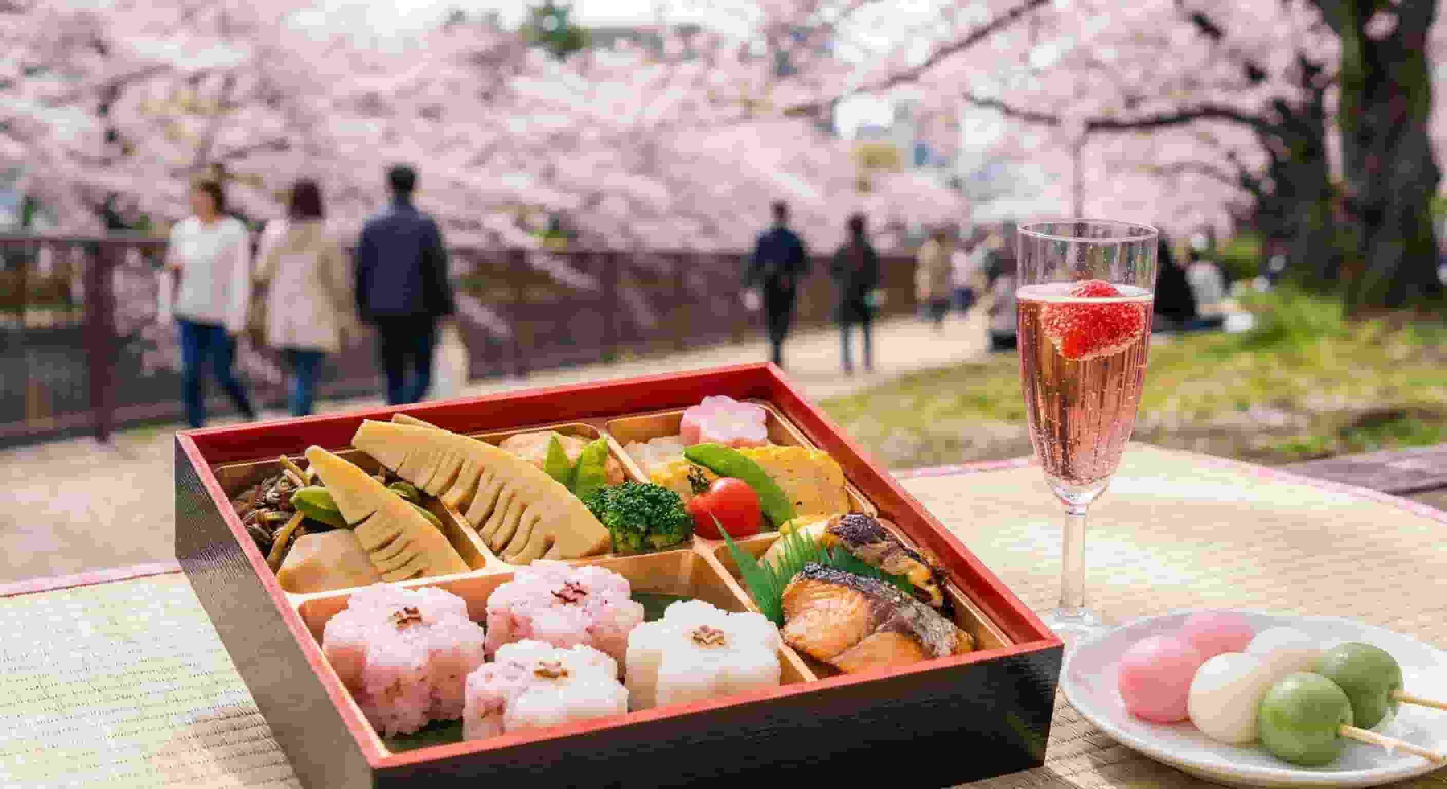 A luxurious Hanami bento box filled with seasonal Japanese ingredients like takenoko (bamboo shoots) and sakura-shaped rice, set against a background of blooming cherry blossoms and a glass of pink champagne, representing the ultimate Tokyo spring food experience.